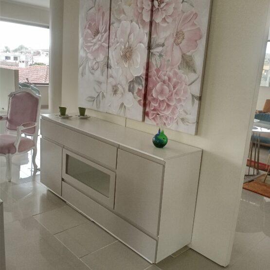 Aparador branco com quadros florais na parede